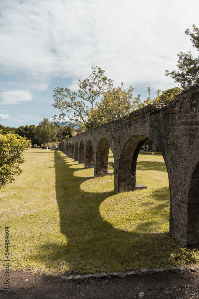 Arcos de acueducto de hacienda colonial antigua con árboles y plantas