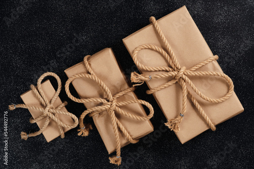 A gift from a woman for a holiday to her men, husband and sons, close-up. Three stylishly wrapped gifts with bows for your beloved family, from above