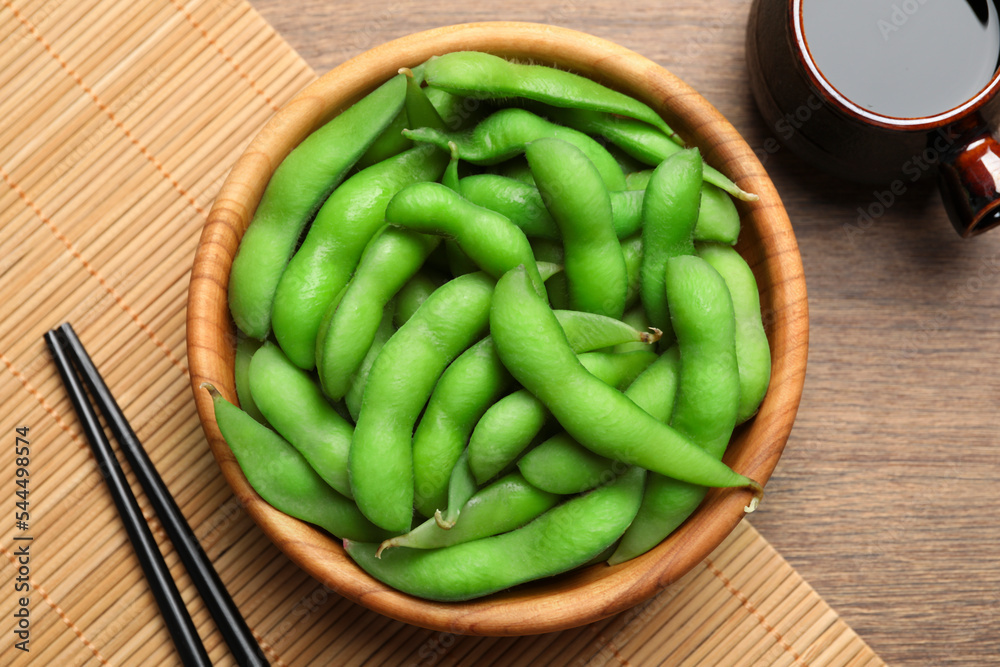 Green edamame beans in pods served with soy sauce on wooden table, flat lay Green edamame beans in pods served with soy sauce on wooden table, flat lay