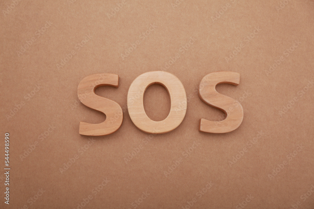 Abbreviation SOS made of wooden letters on light brown background, top view Abbreviation SOS made of wooden letters on light brown background, top view