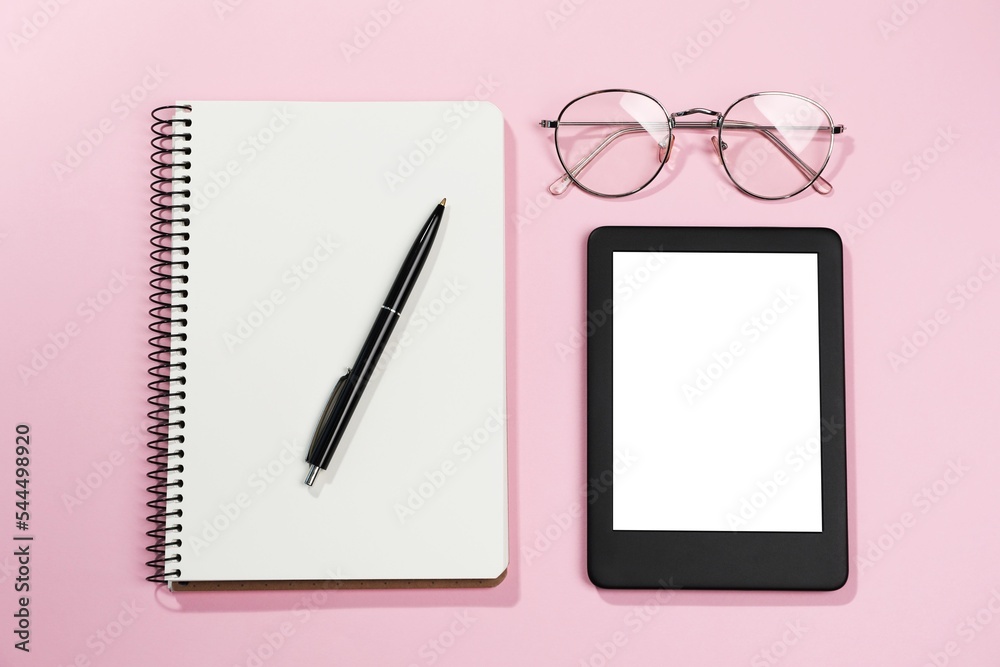 E-book reader, notebook and glasses on pink background, flat lay. Space for text