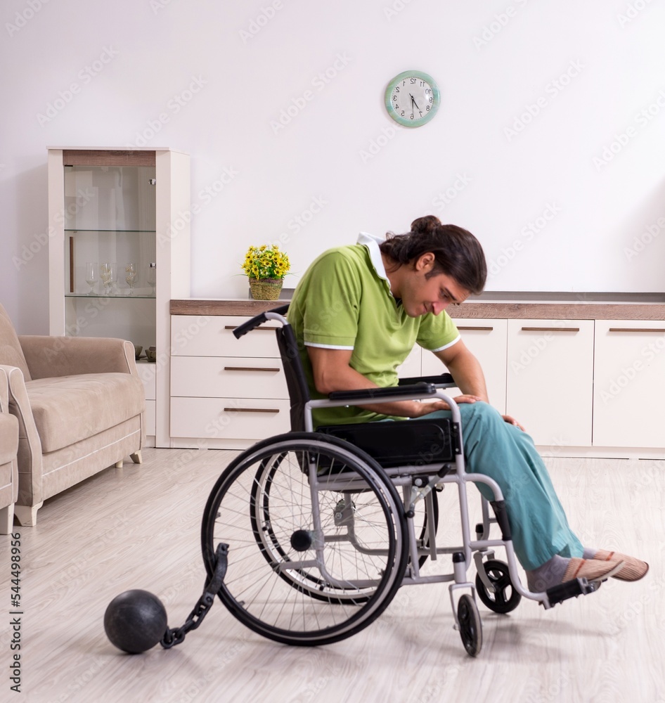 Young male invalid in wheel-chair suffering at home Young male invalid in wheel-chair suffering at home
