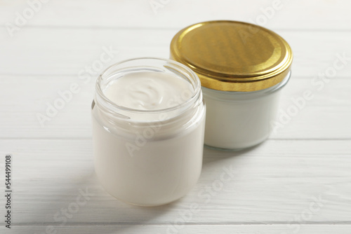 Jars with delicious organic yogurt on white wooden table, closeup