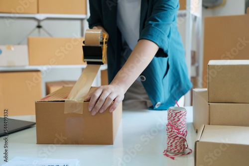 Young woman packing product in box for online order. © ijeab