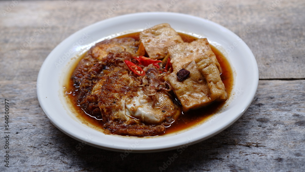 Semur telur dan tahu. Is Indonesian traditional side dish made with sunny side up and tofu cooked with soy sauce and some spices like cinnamon, coriander, pepper, garlic, shallots and chili Semur telur dan tahu. Is Indonesian traditional side dish made with sunny side up and tofu cooked with soy sauce and some spices like cinnamon, coriander, pepper, garlic, shallots and chili