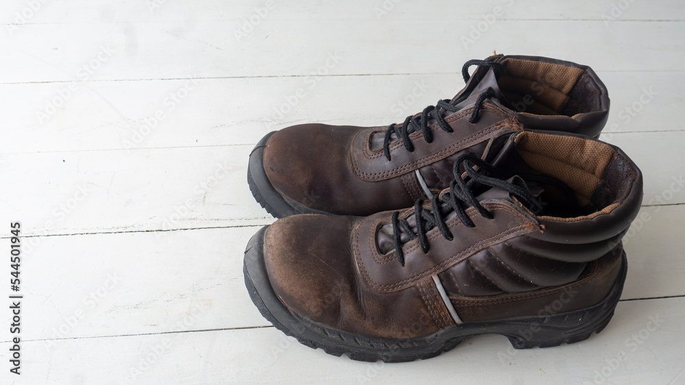 close view of a pair of used rustic safety shoes on top of a white table and a white background