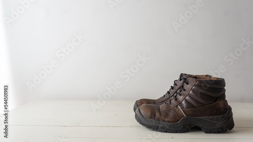 close view of a pair of used rustic safety shoes on top of a white table and a white background