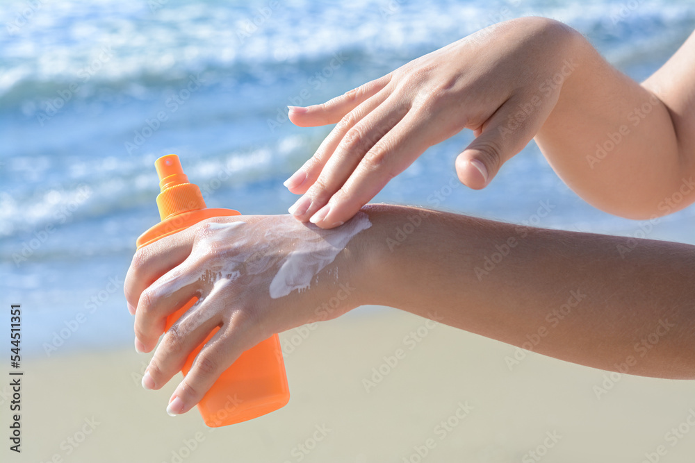 Woman applying sun protection cream on her hand at beach, closeup Woman applying sun protection cream on her hand at beach, closeup