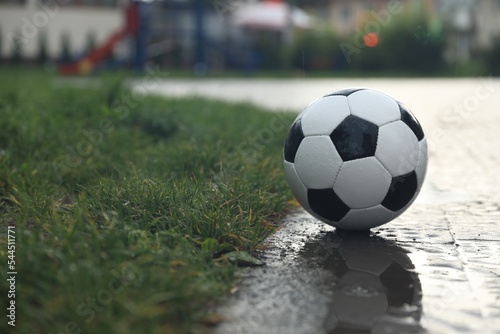 Wet leather soccer ball on street, space for text