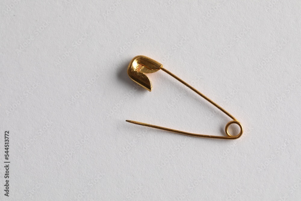Golden safety pin on white background, top view Golden safety pin on white background, top view