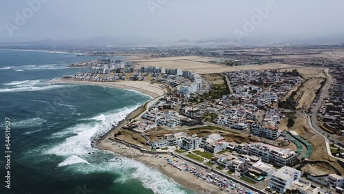 Toma aérea con Drone del Balnearia Punta Hermosa en Lima Perú. Toma de mar en día soleado con casas de fondo photo