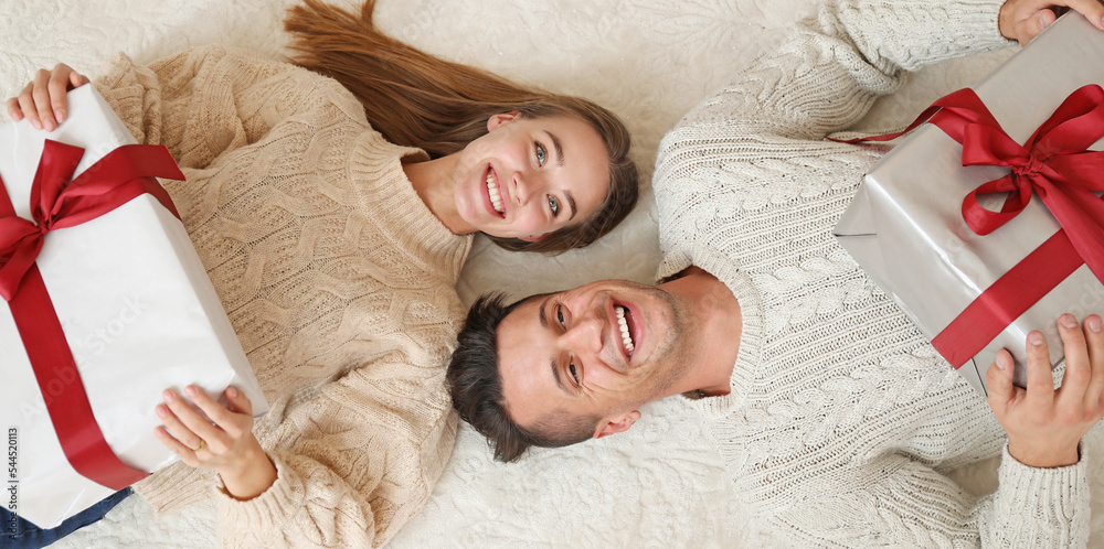Obraz premium Happy young couple with Christmas gifts at home, top view