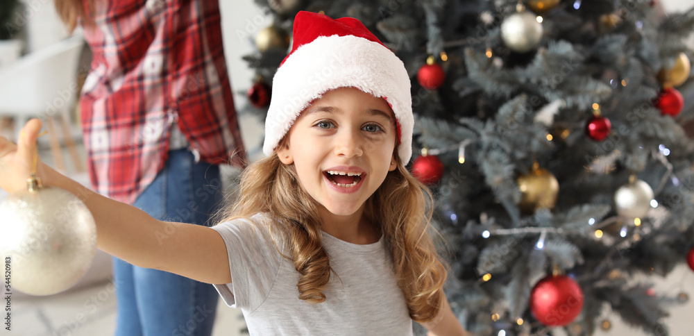 Happy little girl decorating Christmas tree at home Happy little girl decorating Christmas tree at home