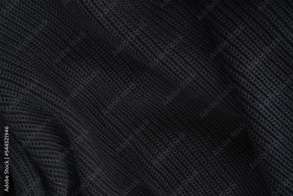 black knitted fabric texture, warm knitted background. soft pleats and draperies on black knitted clothes black knitted fabric texture, warm knitted background. soft pleats and draperies on black knitted clothes