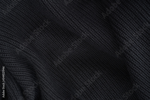 black knitted fabric texture, warm knitted background. soft pleats and draperies on black knitted clothes