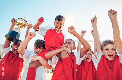 Soccer, winner team and sport trophy celebration in sunshine together after game, contest or competition. Happy, children and shouting for winning with boy kids, diversity and achievement in sports