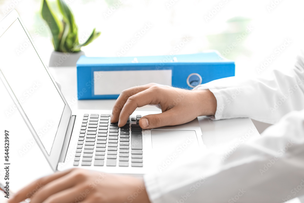 Male doctor working with laptop at table in clinic, closeup Male doctor working with laptop at table in clinic, closeup