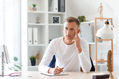 Thoughtful young man writin...