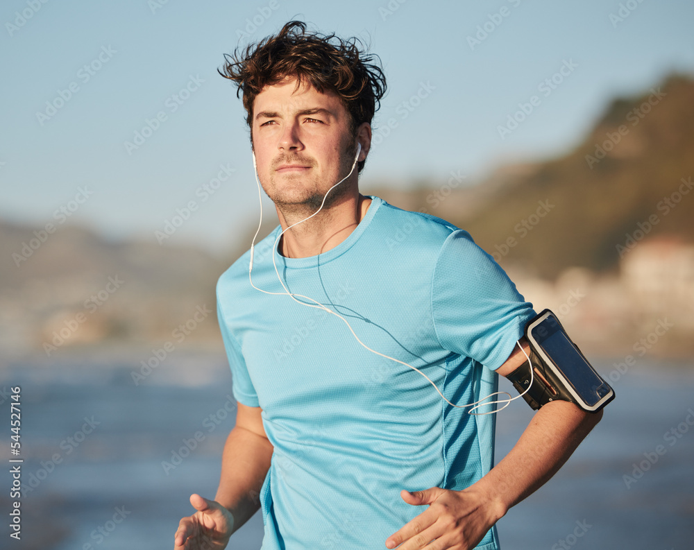 Running, music and man athlete at beach with headphones run by the ocean with audio streaming.
