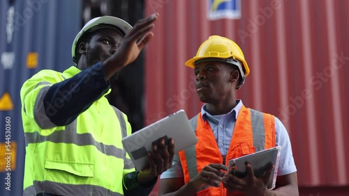 Container import export and logistic concept. Foreman and engineer holding using clipboard and wears PPE to checking inventory or job details with cargo container background.
