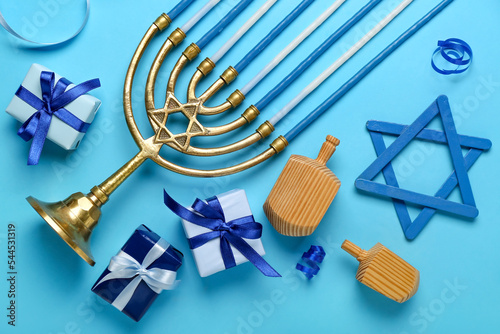 Menorah with dreidels, David star and gifts for Hanukkah celebration on blue background photo