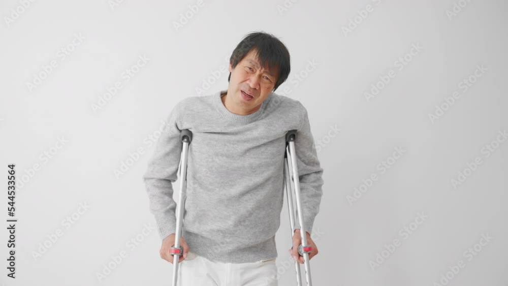 不安そうな表情をする松葉杖をついたミドル男性 医療保険イメージ 不安そうな表情をする松葉杖をついたミドル男性 医療保険イメージ