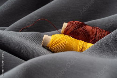 Reel with brown threads on gray silk fabric, macro, texture, close-up. Luxurious bright beautiful background for sewing. Tailoring, the concept of the atelier. High fashion, natural fabrics