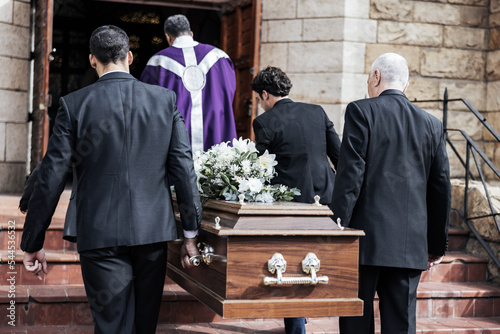 Death, funeral and holding coffin in church for grief, bereavement and with family together on steps. Grieving, sad and congregation in mourning, sad and with goodbye before burial and wood casket. photo