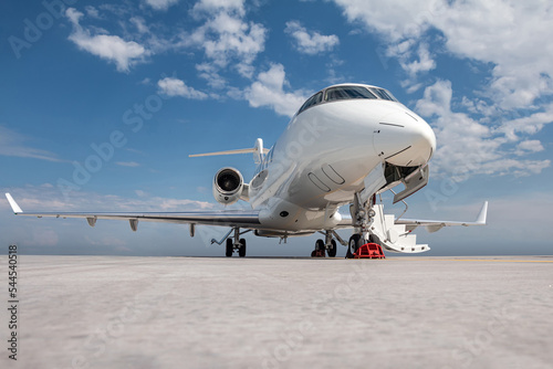 Modern white executive airplane with an opened gangway door at the airport apron
