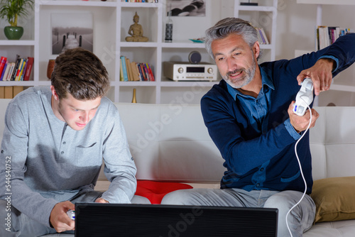 Man and adolescent playing computer game photo