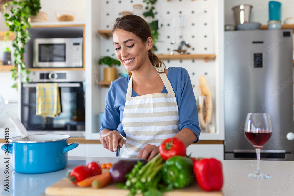 Beautiful young woman stand at modern kitchen chop vegetables prepare fresh vegetable salad for dinner or lunch, young woman cooking at home make breakfast follow healthy diet, vegetarian concept