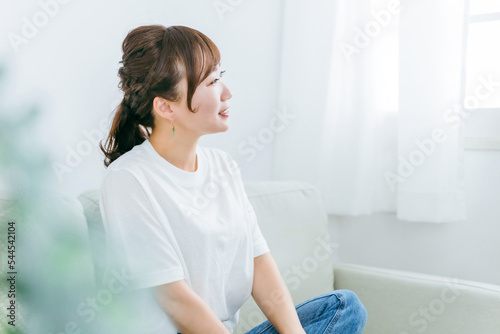 家でリラックスしてソファでくつろぎながら幸せを感じる笑顔の日本人女性の横顔 