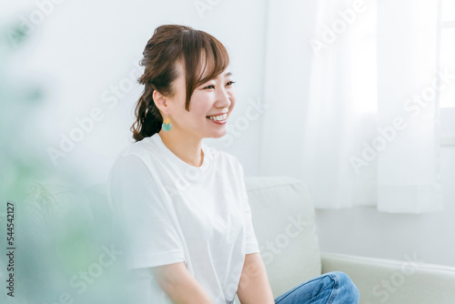 家でリラックスしてソファでくつろぎながら幸せを感じる笑顔の日本人女性の横顔 