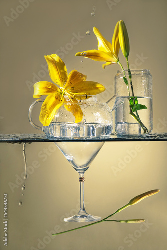 flowers in glass vases. levitation from flowers and glass goblets. still life with flowers and splashes. yellow lilies in a glass. composition of glass goblets and flowers. flying martini glass