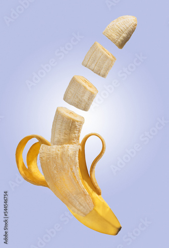cut yellow banana on a purple background. peeled ripe banana. flying fruit. flying food. ripe appetizing banana on a purple background