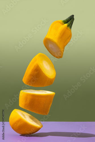 cut yellow zucchini on a green background. flying vegetables. flying food. yellow ripe zucchini on the dining table