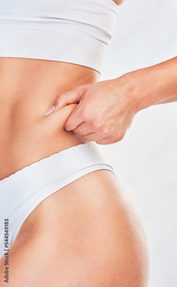 Hand, pinch and woman in underwear her belly fat for weight loss on a white studio background. Overweight, cellulite and fat with a woman with a healthy lifestyle and diet for stomach loss