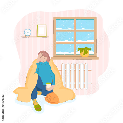 A sad woman with a cat under a blanket in a cold house