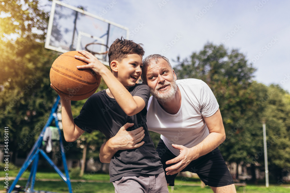 Mature man playing basketball with his son