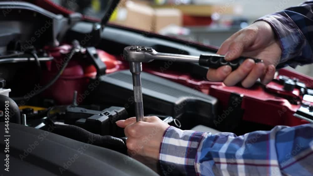 Female auto mechanic unscrewing a nut to replace a car spark plug. Female auto mechanic unscrewing a nut to replace a car spark plug.