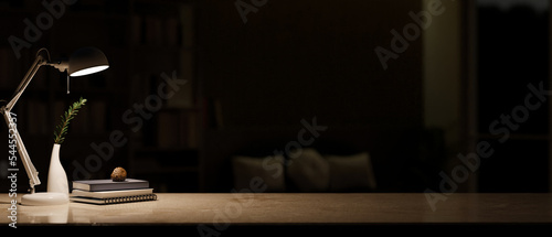 Copy space on marble tabletop with table lamp, books and vase over blurred dark living room