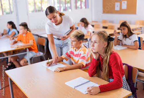 Group of preteen schoolchildren diligently working in class, making notes of teacher lecture..