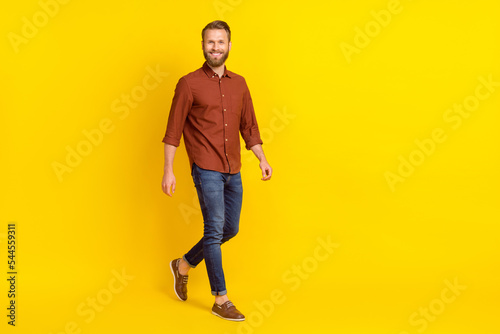 Full body profile portrait of cheerful person have good mood walking isolated on yellow color background