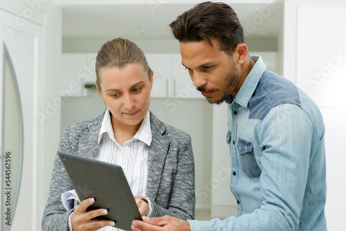Photography real estate agent showing blueprint from tablet to client