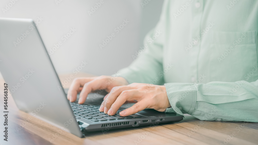 Closeup image of a young man working and typing on laptop computer keyboard on wooden table in the room. Closeup image of a young man working and typing on laptop computer keyboard on wooden table in the room.