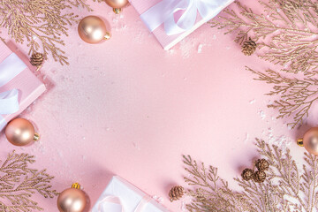 Rose gold Christmas, New Year background with golden christmas tree twigs and balls, holiday gift boxes, decorations, artificial snow, flat lay on pink background copy space