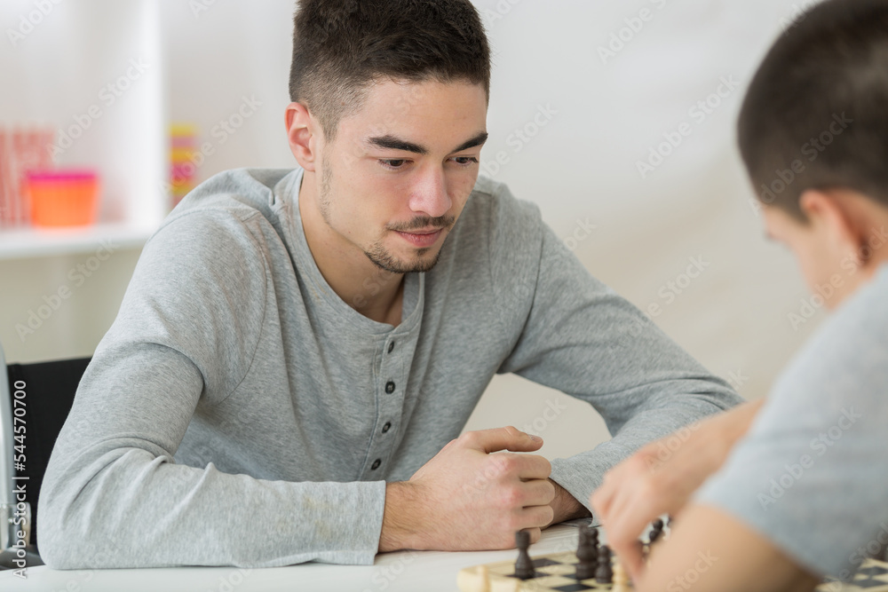 portrait of two young man playing chess - obrazy, fototapety, plakaty 