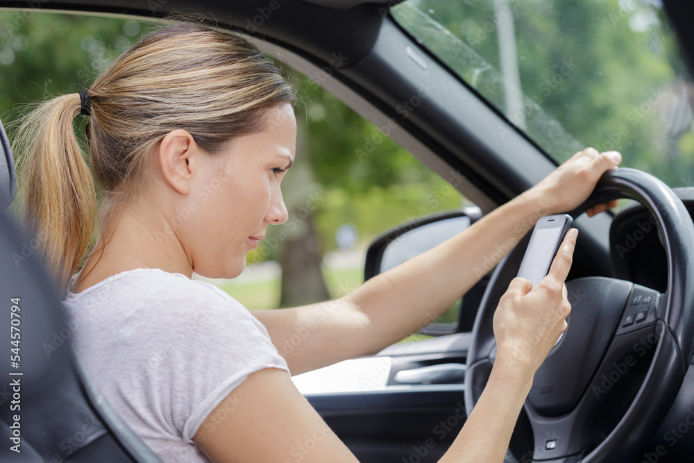 woman driving a car whilst using mobile phone