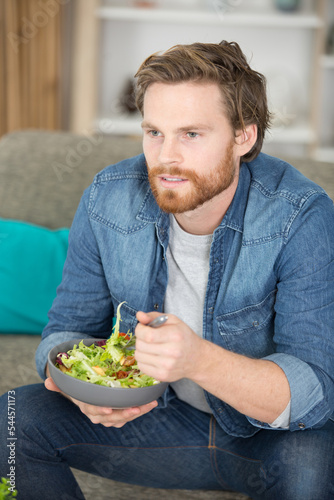 portrait of a man eating a salad in his apartment