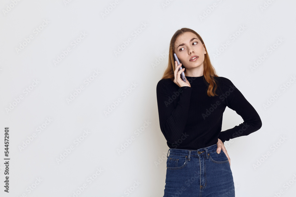 a cute woman in a black turtleneck stands on a white background and talks emotionally on the phone a cute woman in a black turtleneck stands on a white background and talks emotionally on the phone